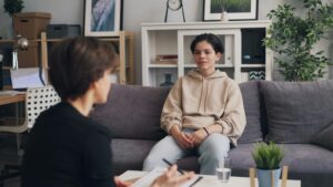 Client sitting across from a therapist, enjoying that they are being supported by a professional who invested in gender affirming care training for therapists